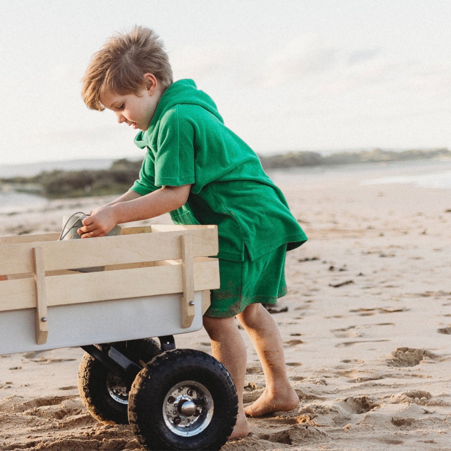 Toddler at the beach in green surf poncho and shorts